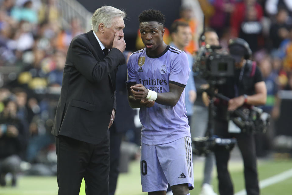 Real Madrid's head coach Carlo Ancelotti, left, speaks to Real Madrid's Vinicius Junior during a Spanish La Liga soccer match between Valencia and Real Madrid, at the Mestalla stadium in Valencia, Spain, Sunday, May 21, 2023. (AP Photo/Alberto Saiz)