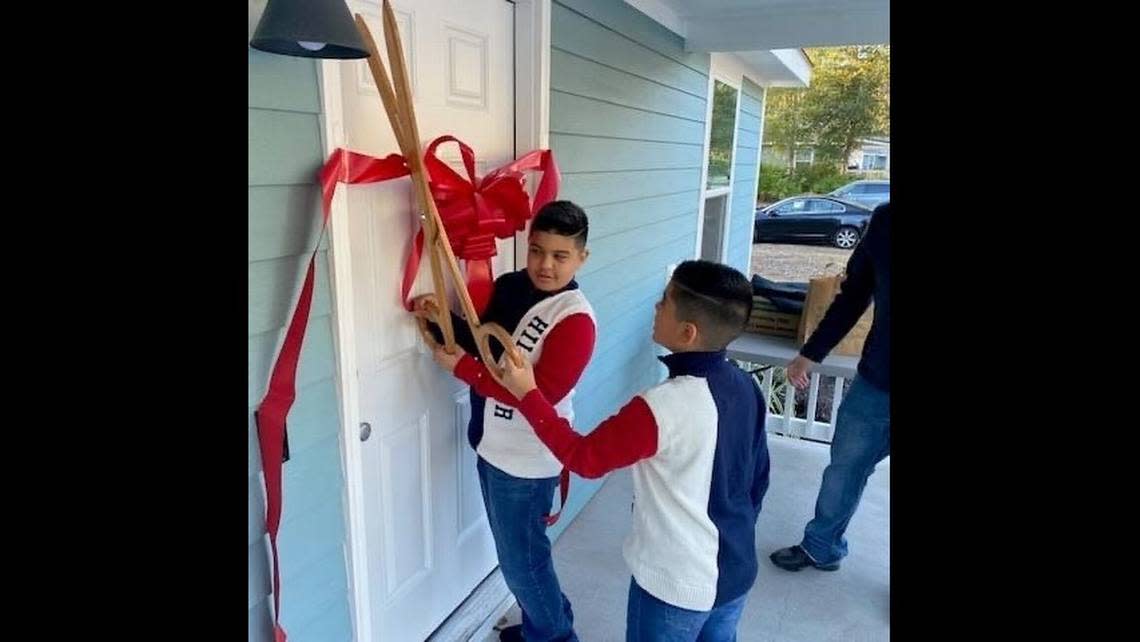 William (left) and Matthew Preciado cut the ribbon on the Preciado’s family’s new home on Friday, Dec. 16. Their home was the last of 16 Habitat for Humanity houses built on land the town donated to Habitat in 2011.