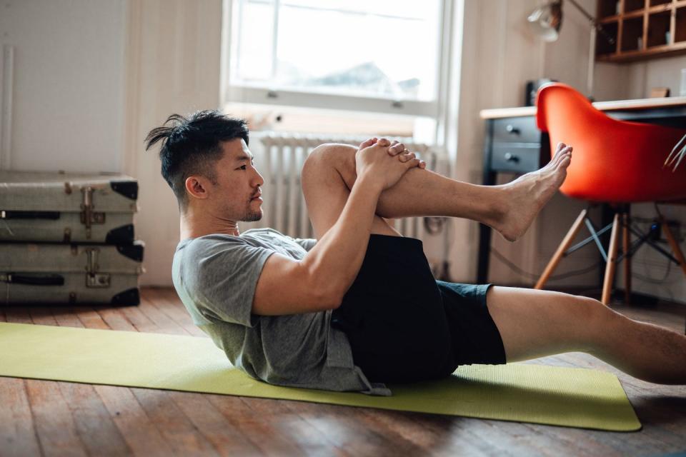 young asian man stretching during workout on exercise mat at home