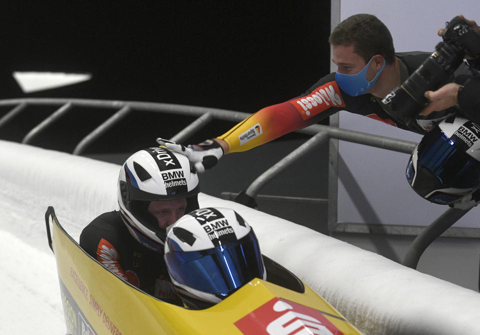 Second placed Johannes Lochner, right, celebrates with first placed Francesco Friedrich and Alexander Schueller, all of Germany, during the two man Bobsled World Cup race in Sigulda, Latvia, Sunday, Nov. 22, 2020. (AP Photo/Roman Koksarov)