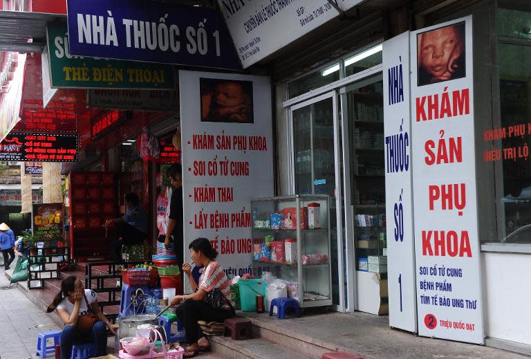 Vendors sit outside a private clinic that offers 4D foetus imaging service, in central Hanoi, on October 22, 2014