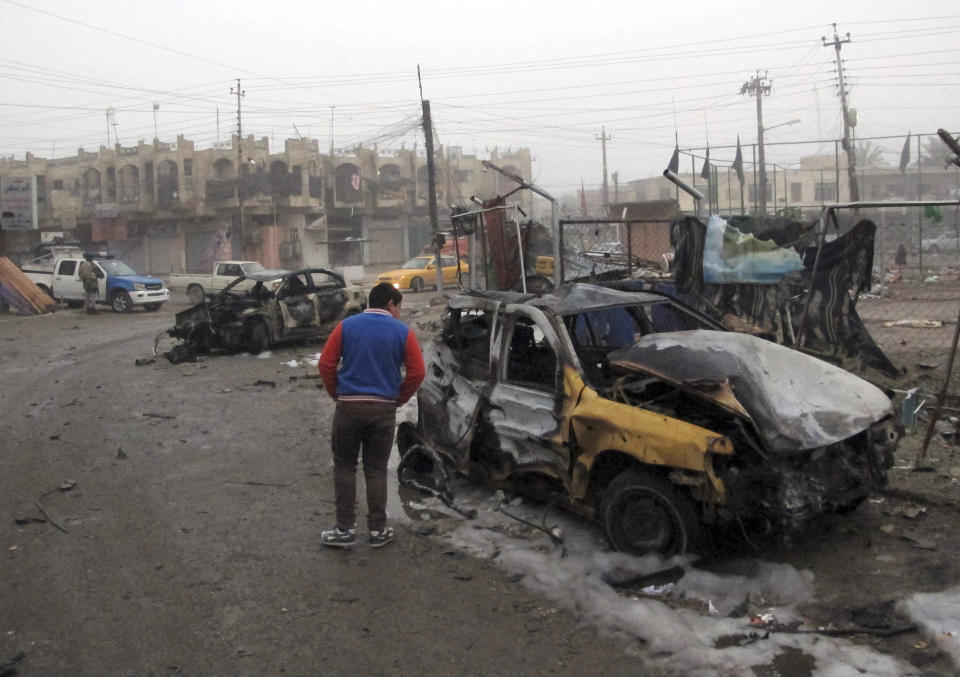 A man inspects the site of a car bomb explosion at a commercial street in al-Ameen district in southeastern Baghdad, Iraq, Sunday, March 16, 2014. A series of car bomb attacks targeting commercial areas and a restaurant killed and wound scores of people, Saturday in Iraq's capital, Baghdad, authorities said. (AP Photo/Khalid Mohammed)