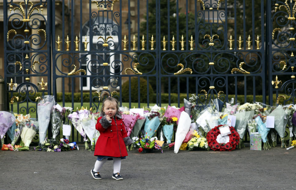 Maisie Cairns (18 months) stands at the gates of Hillsborough Castle in Belfast, Northern Ireland, Saturday, April 10, 2021. People gathered to pay respect to Britain's Prince Philip who died early Friday. Prince Philip, the irascible and tough-minded husband of Queen Elizabeth II who spent more than seven decades supporting his wife in a role that both defined and constricted his life. (AP Photo/Peter Morrison)
