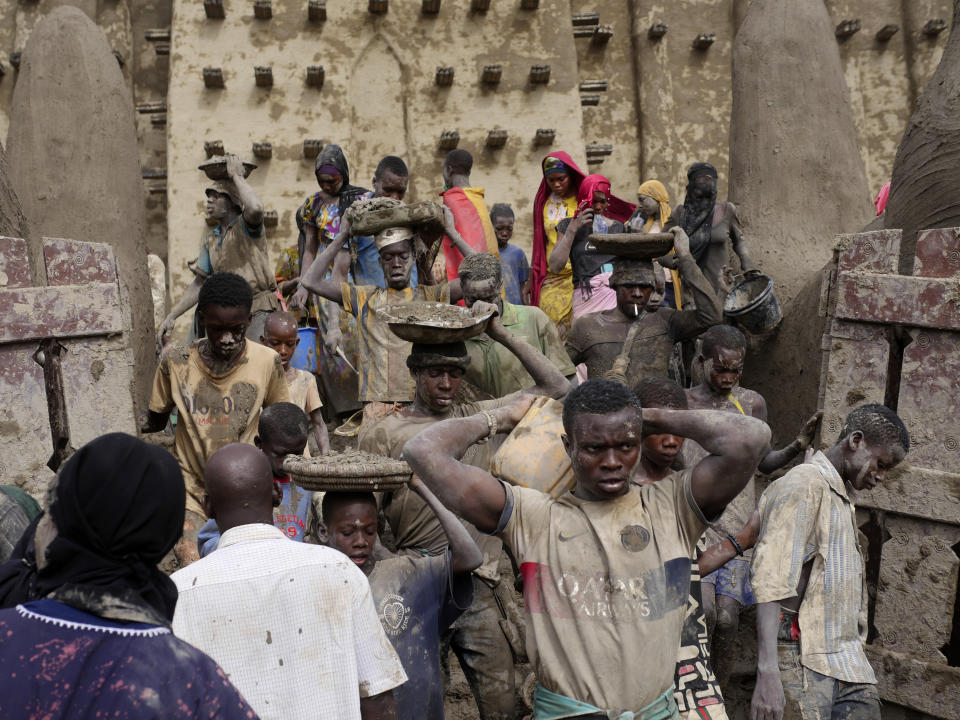 Malians take part in the annual replastering of the world's largest mud-brick building, the Great Mosque of Djenne, Mali, Sunday, May 12, 2024. The building has been on UNESCO's World Heritage in Danger list since 2016. The mosque and surrounding town are threatened by conflict. Djenne's mosque requires a new layer of mud each year before the start of the rainy season in June. (AP Photo/Moustapha Diallo)