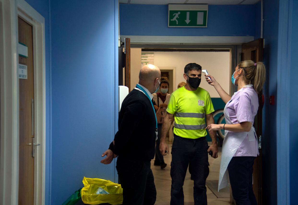 A helth worker takes temperature to a Spanish worker prior to receiving a dose of Pfizer vaccine against COVID-19 at a vaccination centre in Gibraltar on April, 6, 2021. - Gibraltar, a tiny British territory on Spain's southern tip, has become one of the first places in the world to vaccinate the bulk of its adult population against the coronavirus, allowing virus restriction to be lifted and life to almost return to normal. (Photo by CRISTINA QUICLER / AFP) (Photo by CRISTINA QUICLER/AFP via Getty Images)