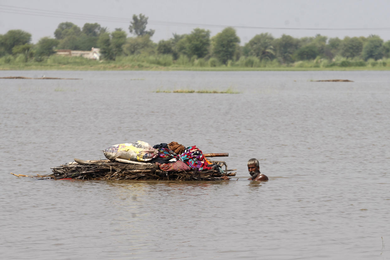 A displaced man transports usable belongings salvaged from his flood-hit home across a flooded area in the Shikarpur district of Sindh province, Pakistan, Tuesday, Aug. 30, 2022. (Fareed Khan/AP)