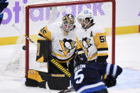 Pittsburgh Penguins goaltender Tristan Jarry (35) makes a save on Winnipeg Jets' Brenden Dillon (5) as Penguins' Kris Letang (58) watches during the first period of an NHL hockey game Monday, Nov. 22, 2021, in Winnipeg, Manitoba. (Fred Greenslade/The Canadian Press via AP)