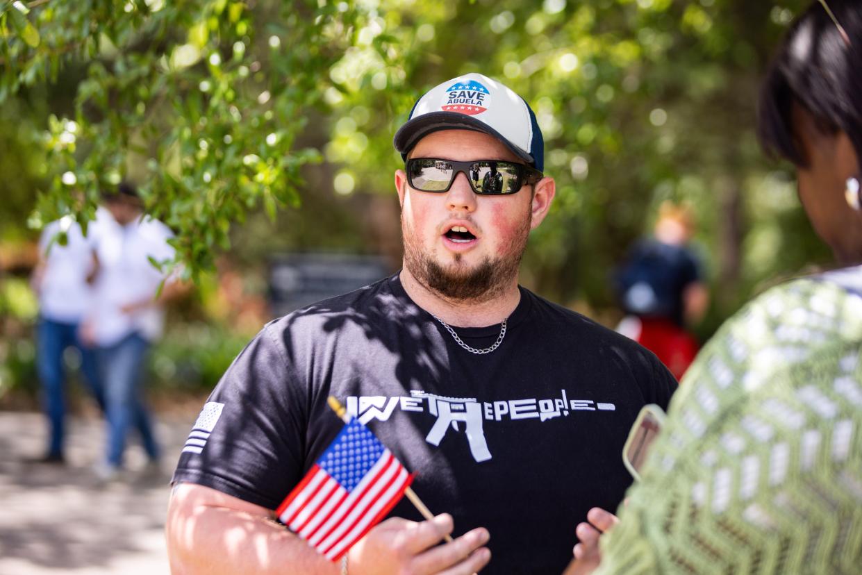 Waving an American flag and playing patriotic music, Jacob Russell, a student at Georgia Southern, talks to a reporter while sitting across from the pro-Palestinian supporters.