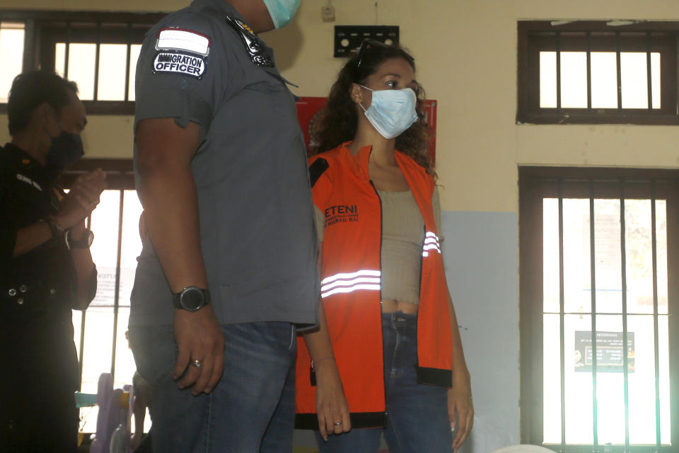 Heather Mack of Chicago, Ill., right, is escorted by Indonesian immigration officers at Immigration detention center in Jimbaran, Bali, Indonesia on Friday, Oct. 29, 2021. The American woman convicted of helping to kill her mother on Indonesia's tourist island of Bali in 2014 walked free from prison Friday after serving seven years of a 10-year sentence and will be deported to the United States. (AP Photo/Firdia Lisnawati)