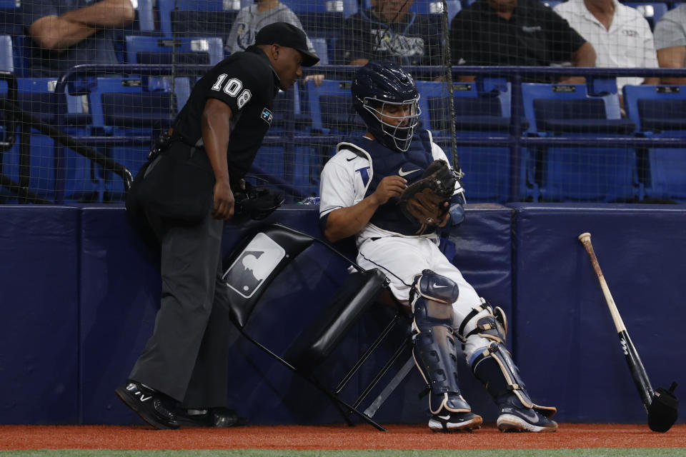 Home plate umpire Malachi Moore looks in to the glove of Tampa Bay Rays catcher Francisco Mejia after Meijia collided with wall making a catch on a ball hit by Texas Rangers' Norman Lowe during the fifth inning of a baseball game Friday, Sept. 16, 2022, in St. Petersburg, Fla. (AP Photo/Scott Audette)