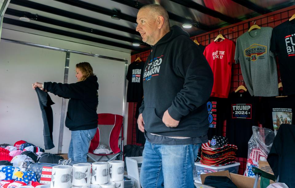 Monica, left, and Mike Domanico, right, from Warrington, selling Trump merchandise including shirts, flags, hats, and toilet paper with Present Joe Biden's face on it, at the street rally for former President Donald J. Trump across from the Newtown Athletic Center in Newtown on Saturday, April 13, 2024.