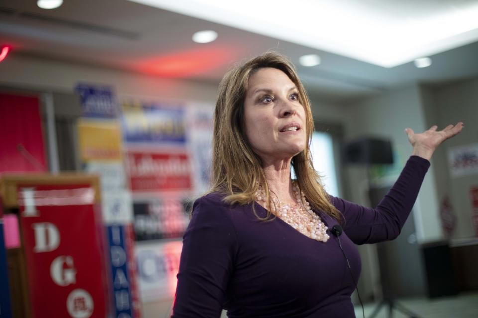 Janice McGeachin gestures emphatically in a room covered with posters.