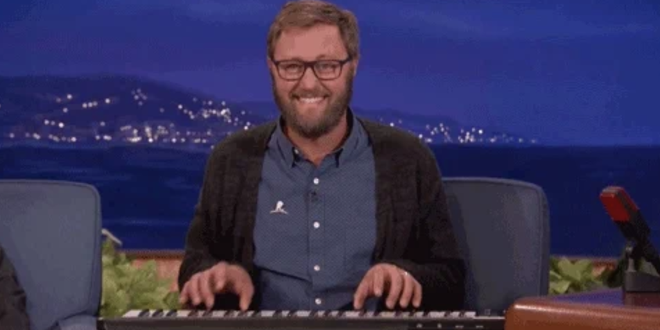 Person smiling while playing a keyboard on a talk show set