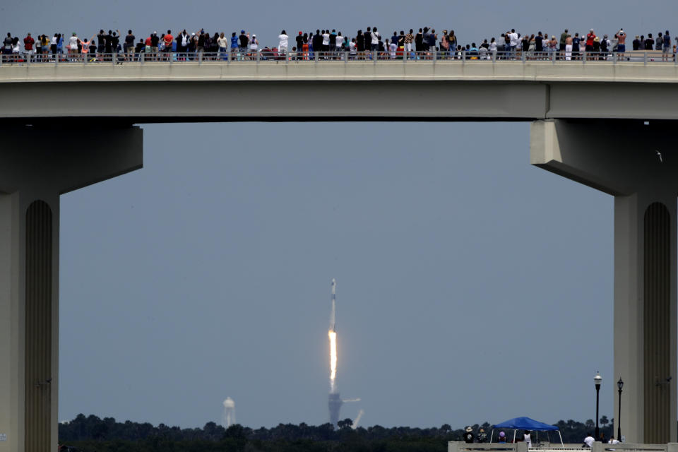 Spectators watch from a bridge in Titusville, Fla. as SpaceX Falcon 9 lifts off with NASA astronauts Doug Hurley and Bob Behnken in the Dragon crew capsule, Saturday, May 30, 2020 from the Kennedy Space Center at Cape Canaveral, Fla. The two astronauts are on the SpaceX test flight to the International Space Station. For the first time in nearly a decade, astronauts blasted towards orbit aboard an American rocket from American soil, a first for a private company. (AP Photo/Charlie Riedel)