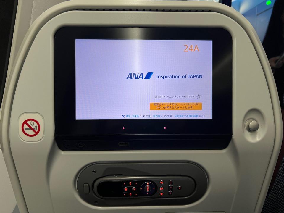 The seatback TV screen with the remote stored below it.