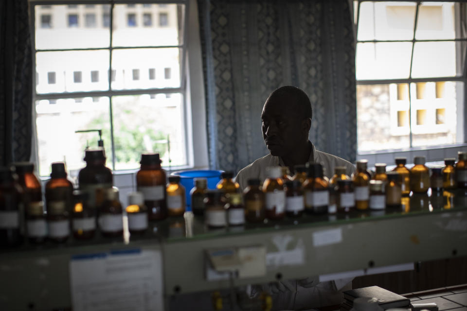 In this photo taken Thursday, Nov. 7, 2019, biochemist Denys Rukarata works in the room where he tests locally-produced oral liquid morphine for purity, as well as other medicines, at the Pharmaceutical Laboratory of Rwanda where the country's liquid morphine is made from powder, in Butare, Rwanda. While people in rich countries are dying from overuse of prescription painkillers, people in Rwanda and other poor countries are suffering from a lack of them, but Rwanda has come up with a solution to its pain crisis - it's morphine, which costs just pennies to produce and is delivered to households across the country by public health workers. (AP Photo/Ben Curtis)