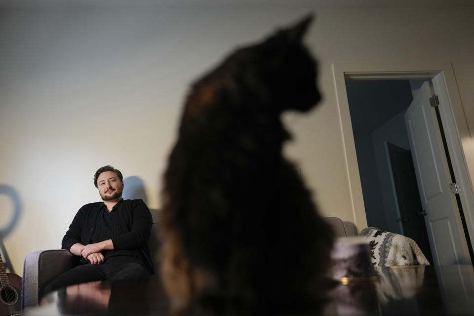 Ashton Colby is photographed with his cat Teddy in his apartment in Columbus, Ohio, on Thursday, Jan. 18, 2024. Ohio Gov. Mike DeWine announced proposals this month that transgender advocates say could block access to gender-affirming care provided by independent clinics and general practitioners, leaving thousands of adults scrambling for treatment and facing health risks. Colby, 31, fears the clinic where he gets the testosterone he has taken since age 19 would no longer offer it. (AP Photo/Carolyn Kaster)