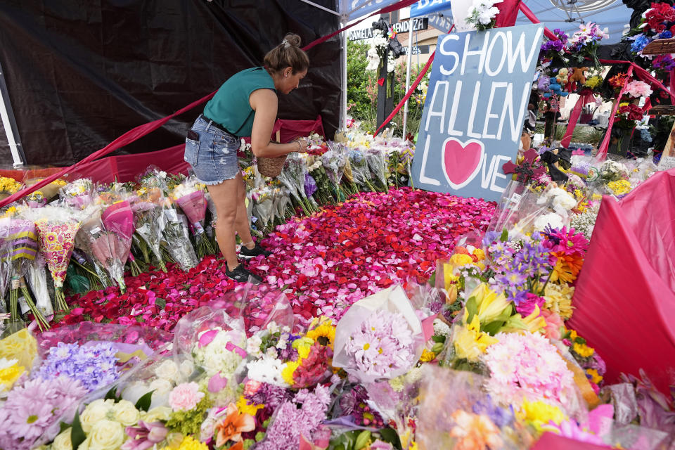 Mahboubeh Gorgband, of McKinney Texas, lays flower pedals at a makeshift memorial by the mall where several people were killed, Wednesday, May 10, 2023, in Allen, Texas. (AP Photo/Tony Gutierrez)