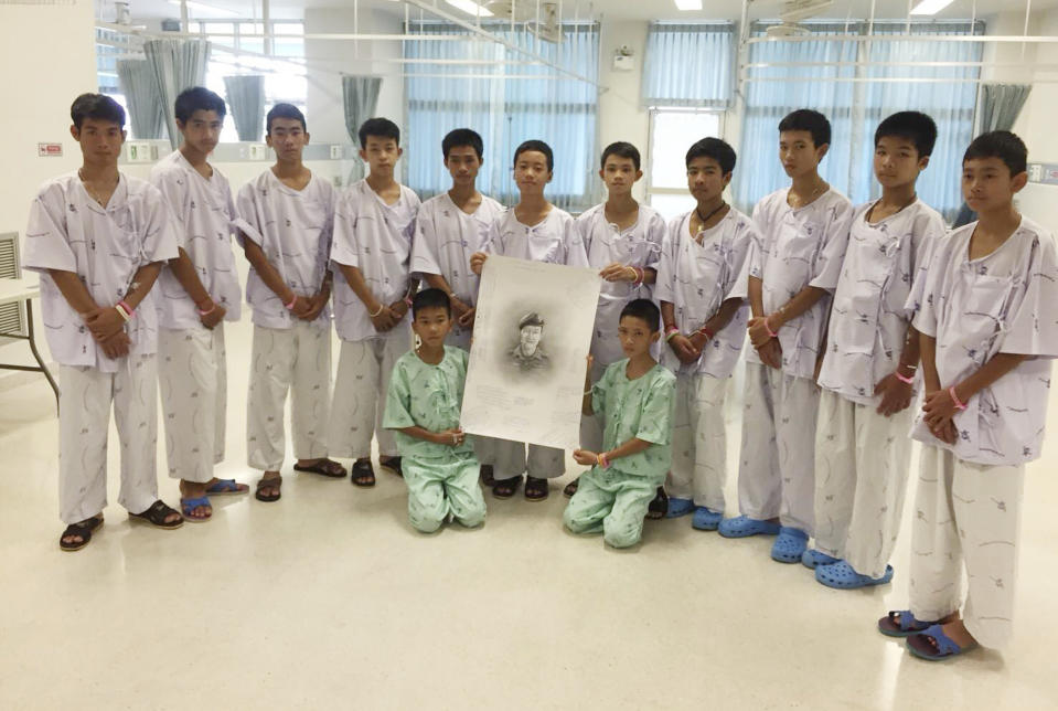 <em>The Wild Boars football team members pose with a sketch of the Thai Navy SEAL diver who died while trying to rescue them (AP)</em>