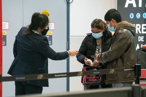 Two travellers are pictured at Pearson International Airport on Feb. 23. Air passengers landing in Canada who refuse to quarantine in a hotel could face a $5,000 fine starting on Friday.  (Sam Nar/CBC - image credit)