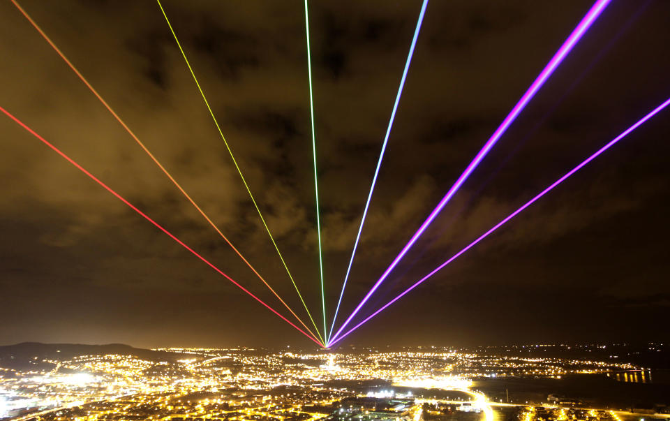 The Global Rainbow is projected into the night sky from Scrabo Tower, Newtownards, Northern Ireland, Friday, March 16, 2012. The large scale outdoor laser projection created by New York artist Yvette Mattern is visible across the night sky, the event signals 100 days to go until the opening of the London 2012 Festival which is a tweleve-week festival of arts running parallel to the Olympic Games taking place in London. (AP Photo/Peter Morrison)