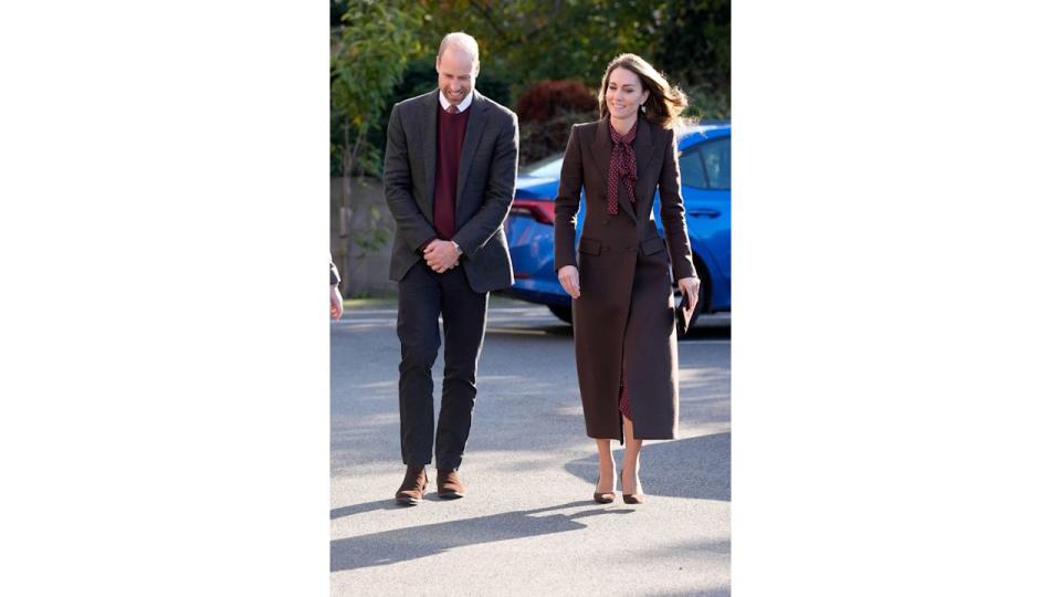 The Prince and Princess of Wales in brown coat walking