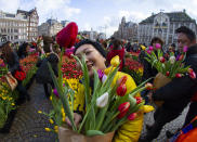 Scores of people pick free tulips on Dam Square in front of the Royal Palace in Amsterdam, Netherlands, Saturday, Jan. 18, 2020, on national tulip day which marks the opening of the 2020 season. (AP Photo/Peter Dejong)