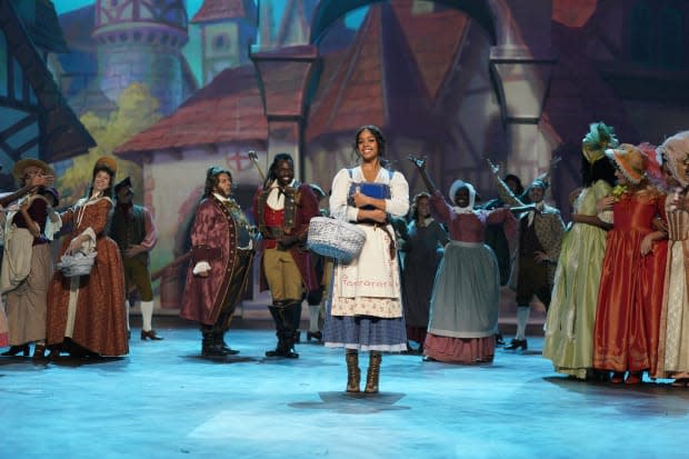 Belle (H.E.R.) in a modern-leaning denim dress, accessorized with a wicker basket and a book.<p>Photo: Christopher Willard/Courtesy of ABC</p>