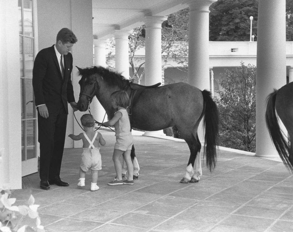 <p>Outside the White House's Oval Office, President Kennedy and his children, John and Caroline, play with their pony, Macaroni.</p>