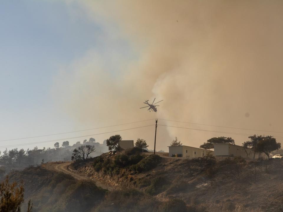 A firefighter helicopter drops water as teams conduct extinguishing works by land and air to control wildfires across Greece's Rhodes island on July 22, 2023.