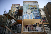 Vecinos en su balcón bajo un mural del astro del fútbol Carlos Tevez en el barrio de Fuerte Apache en Buenos Aires, Argentina, el miércoles 10 de junio de 2020. (AP Foto/Natacha Pisarenko)