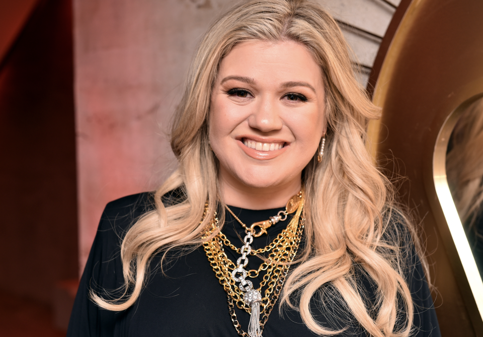 Headshot of smiling Kelly wearing strands of rope necklaces