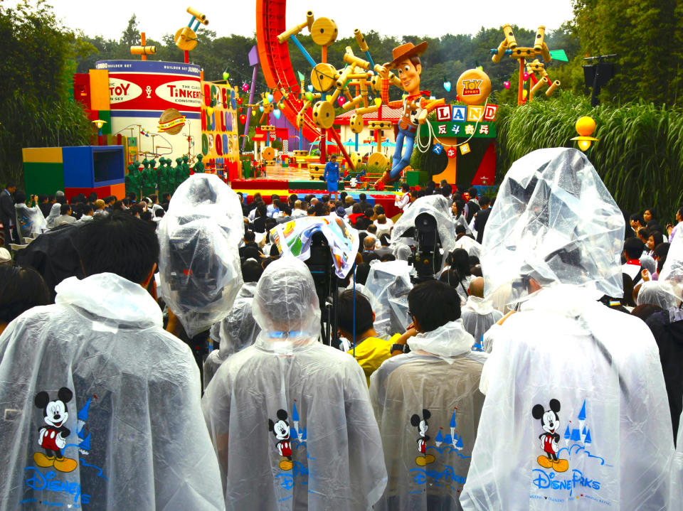 Journalists wearing ponchos stand in the rain during the opening ceremony of Toy Story Land at Hong Kong Disneyland November 17, 2011. The new themed area, inspired by the global blockbuster "Toy Story" trilogy, is the first phase of the resort's expansion project.  REUTERS/Bobby Yip (CHINA - Tags: TRAVEL SOCIETY BUSINESS MEDIA) - GF2E7BH0L7701