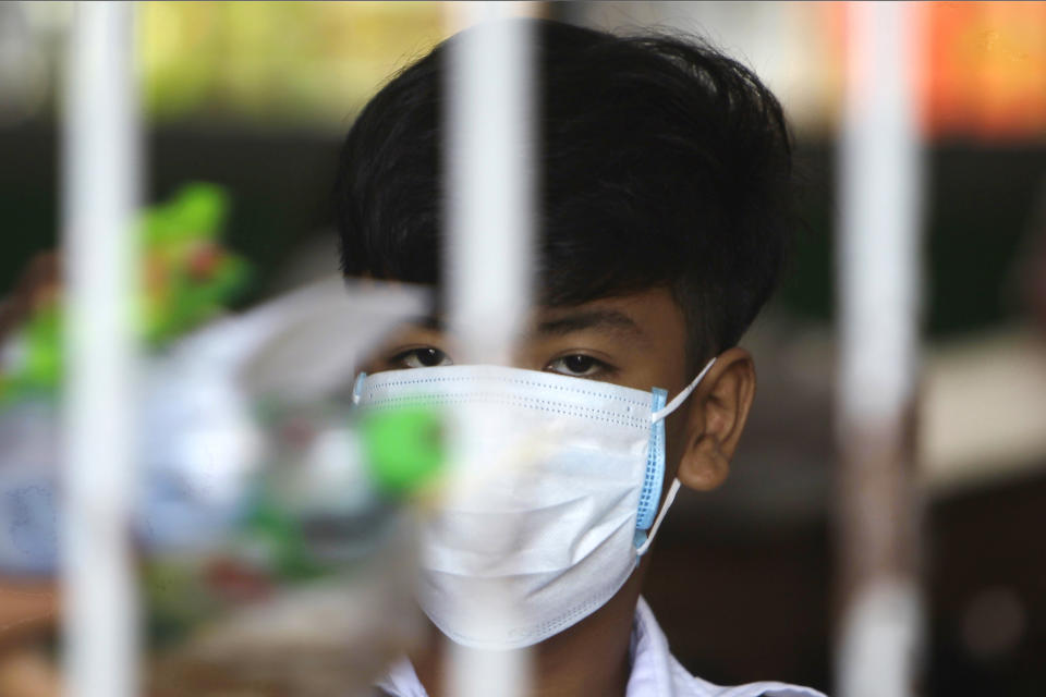A school student wearing a face-mask, looks on from a class room during a morning class at Santhormok high school, in Phnom Penh, Cambodia, Monday, Nov. 2, 2020. Schools throughout Cambodia reopened Monday for the first time since March but with class sizes and hours limited by coronavirus precautions. (AP Photo/Heng Sinith)