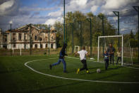 Boys play soccer next to a destroyed school, background, in Izium, Ukraine, Monday, Oct. 3, 2022. (AP Photo/Francisco Seco)