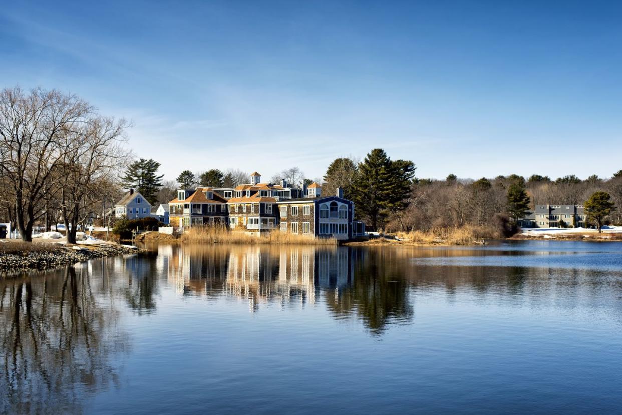 a large mansion reflecting off the waters of the batson river in kennebunkport maine on a cold sunny winter day