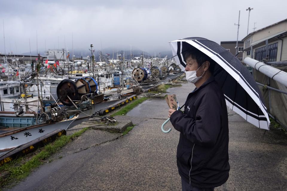 A fisherman stands at a port in Wajima in the Noto peninsula facing the Sea of Japan, northwest of Tokyo, Sunday, Jan. 7, 2024. Monday's temblor decimated houses, twisted and scarred roads and scattered boats like toys in the waters, and prompted tsunami warnings. (AP Photo/Hiro Komae)