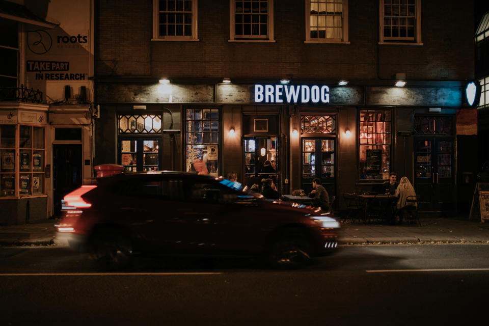 BRIGHTON, ENGLAND - October 26th, 2018: Night view of Brewdog brewery pub facade with people sitting and drinking beer in the terrace, viewed from the opposite sidewalk, in Brighton, Sussex, England.