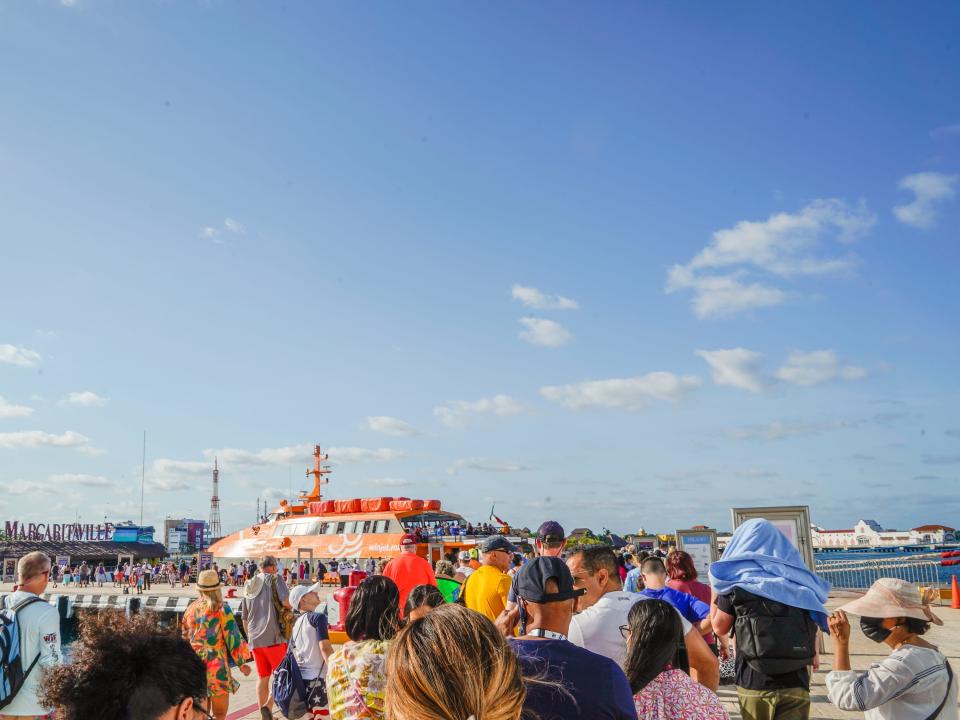 People line up for a ferry with blue skies