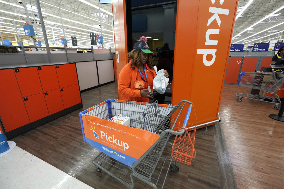 FILE- In this Nov. 9, 2018, file photo Walmart associate Monique Mays places online orders in a pickup tower where customers can retrieve their purchases at a Walmart Supercenter in Houston. Plenty of major retailers are offering easier ways for customers to pick up items ordered online beyond the service desk. Walmart is adding lockers and big giant kiosks that spit out online orders. (AP Photo/David J. Phillip, File)