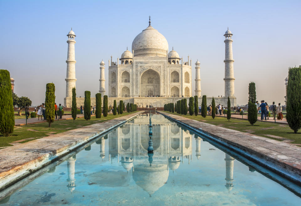 Taj Mahal with reflective pool in foreground and visitors walking around