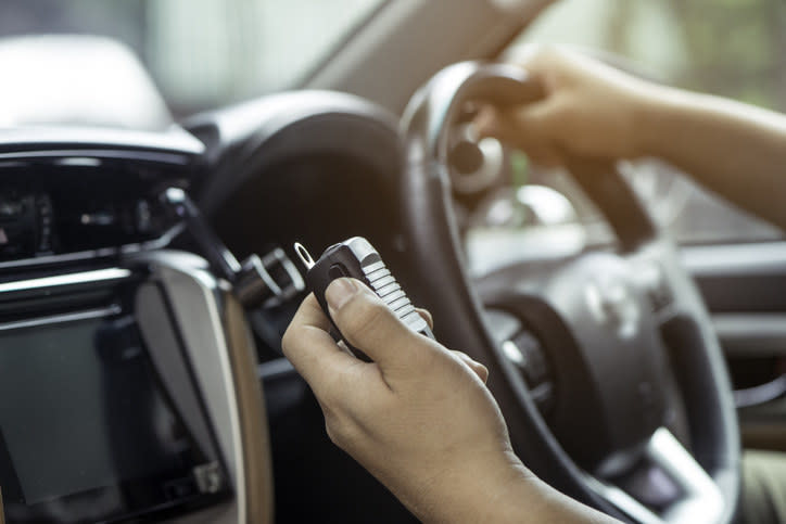 A person's hand holding a wireless transmitter box inside a car