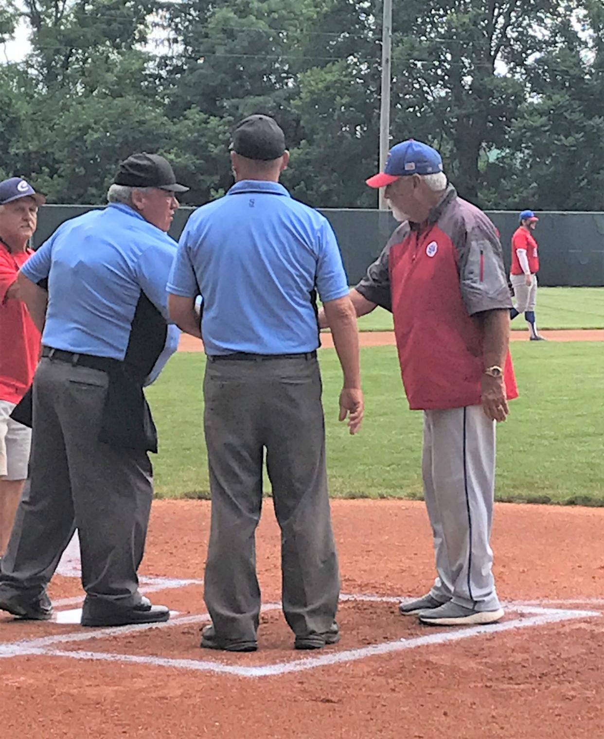 Veteran Cambridge Post 84 manager Ron Antill, right, meets with umpires during the pre-game conference during last Sunday's Coshocton Post 65 Ben Tufford Memorial Tournament at Lake Park in Coshocton. This weekend, Antill and his Post 84 squad will look to defend last season's title as they host the 30th Annual Don Coss Tournament at Don Coss Stadium.