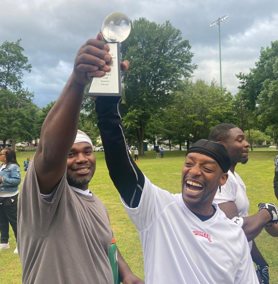 Members of the "White Team" hoist the championship trophy after beating the "Blue Team" in the Poughkeepsie High School alumni football game last Saturday.