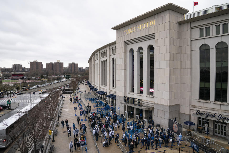 Spectators wait on a security line outside Yankee Stadium before an opening day baseball game against the Toronto Blue Jays, Thursday, April 1, 2021, in the Bronx borough of New York. Fans are back at the ballpark in limited numbers after they were shut out completely during the regular season last year due to the COVID-19 pandemic.(AP Photo/John Minchillo)