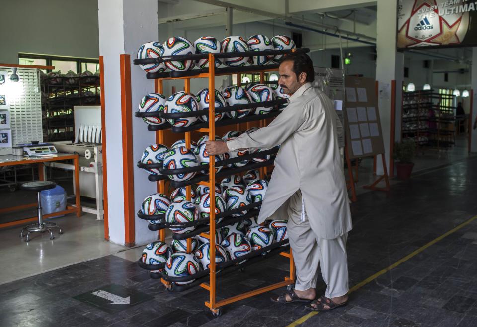 An employee takes finished balls out of the production area inside the soccer ball factory that produces official match balls for the 2014 World Cup in Brazil, in Sialkot, Punjab province