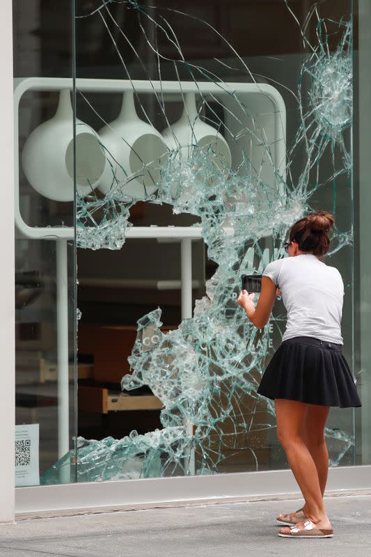 A woman takes a picture of a looted shop in the Gold Coast area in Chicago