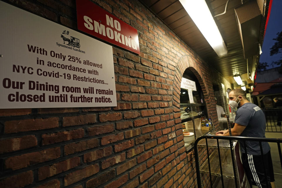 A customer waits for food he ordered at L&B Spumoni Gardens, Sunday, Oct. 4, 2020, in the Brooklyn borough of New York. The restaurant, located in a neighborhood where coronavirus cases are rising, may have to close down its outdoor seating area and restrict itself to takeout and delivery only if New York's mayor imposes restrictions he announced Sunday, pending approval by the state. (AP Photo/Kathy Willens)