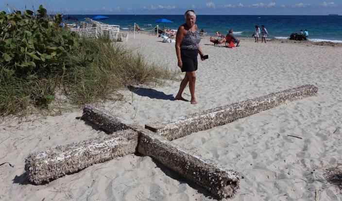 Aglair Rigos checks out a cross on the Galt Ocean Mile behind the Ocean Manor Beach Resort, in Fort Lauderdale, Florida, on Tuesday, Feb. 5, 2019. The large, barnacle-covered wooden cross washed ashore along the South Florida beach on Saturday.