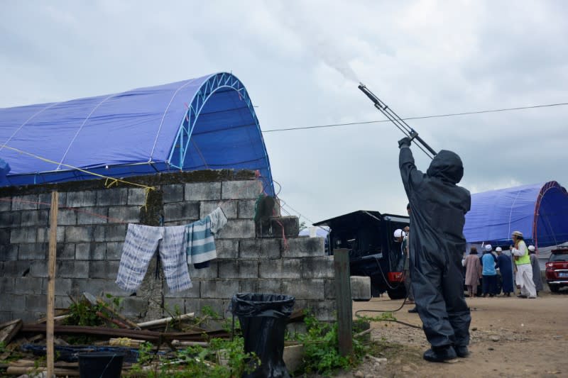 A police officer wearing a protective suit sprays disinfectants on a tent intended for the Muslim pilgrims to stay for mass gathering supposed to be held amid the spread of coronavirus disease in Gowa